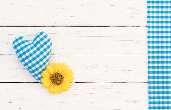Cute blue heart with yellow flower on white wooden background with copy space