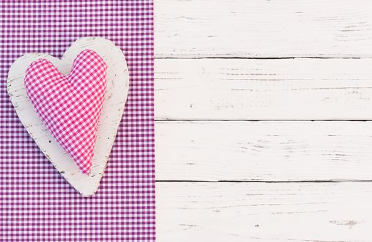 Cute pink heart on purple fabric and white wooden background with copy space

