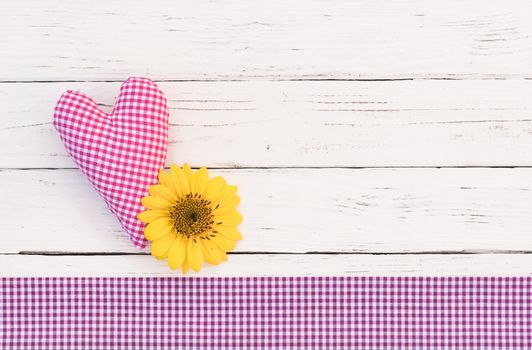 Cute pink heart and yellow flower head on white wooden background with copy space

