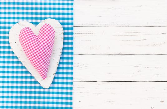 Pink heart on blue fabric border and white wood background with copy space