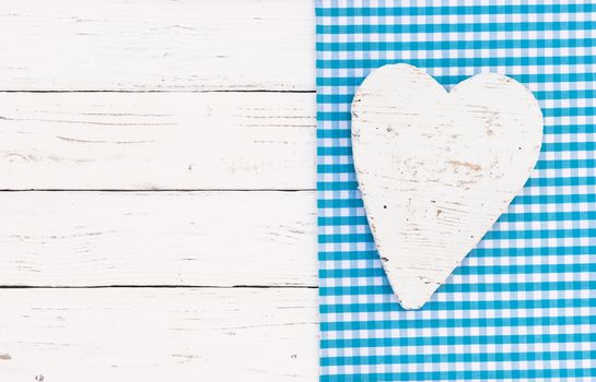 White wooden heart on blue fabric and wood background with copy space