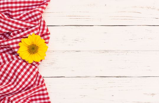 Red checked tablecloth with blossom on white wooden background with copy space