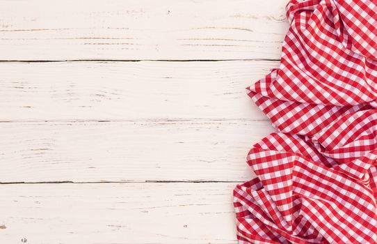 Rustic white wooden table surface with red checkered cloth, top view