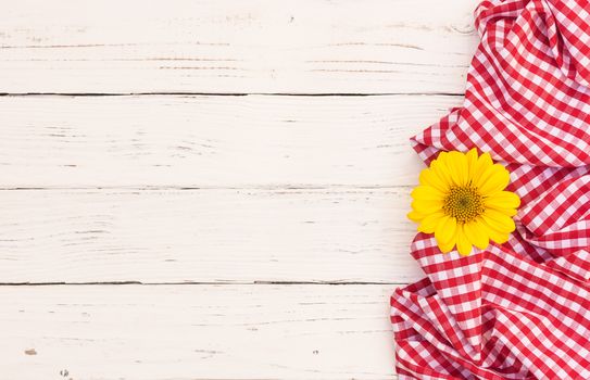 White wood table with red tablecloth and yellow blossom with copy space
