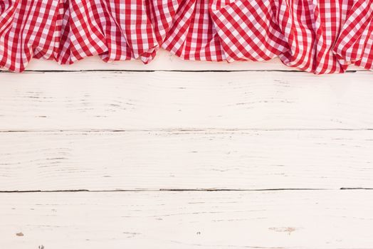 Rustic white wooden table surface with red checkered cloth, top view