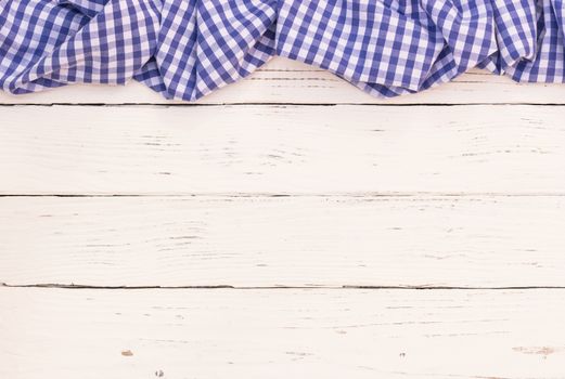 Rustic white wooden table surface with blue checkered cloth, top view
