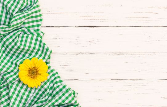 Green checked tablecloth with blossom on white wooden background with copy space