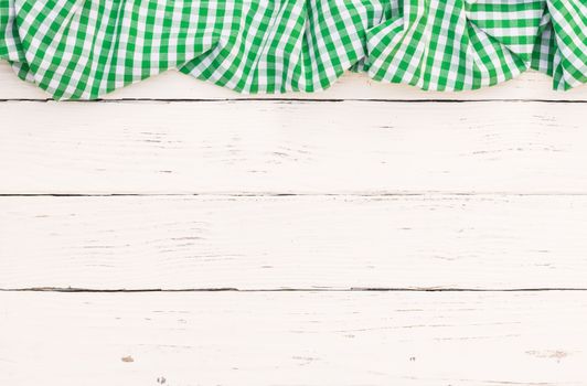 Rustic white wooden table surface with green checkered cloth, top view