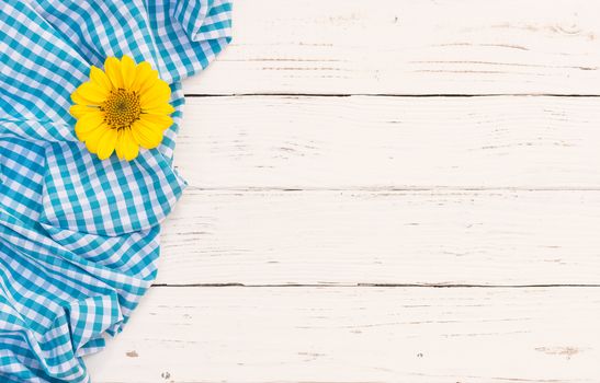Blue checked tablecloth with blossom on white wooden background with copy space