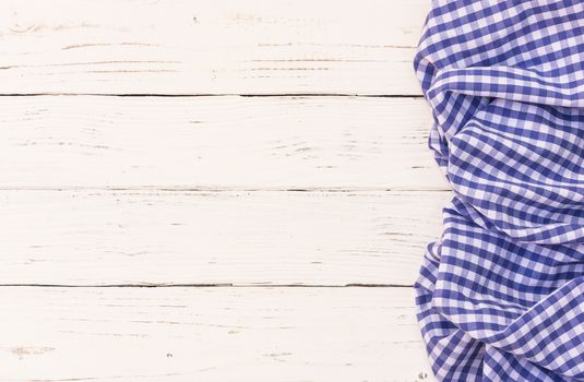 Rustic white wooden table surface with blue checkered cloth, top view