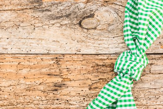 Rustic old wooden table surface with green checkered cloth, top view