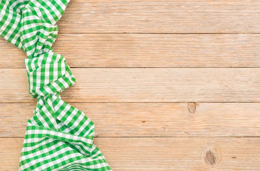 Green checked tablecloth on wooden table, top view with copy space