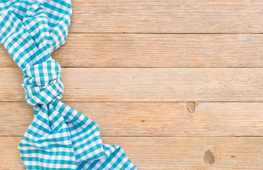 

Knotted blue checked tablecloth on wooden table background, top view