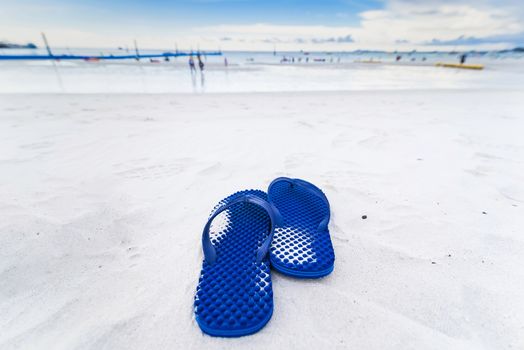 Blue flip flops on the sandy beach, sandals on beach.