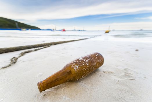 Brown glass bottle on Tawaen Beach in the day time on Koh Lan island.