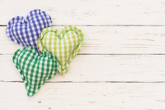 Blue and green hearts on white wooden background with copy space