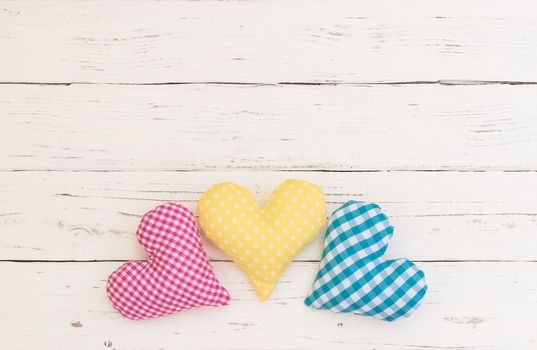 Pink, yellow and blue hearts on white wood background with copy space
