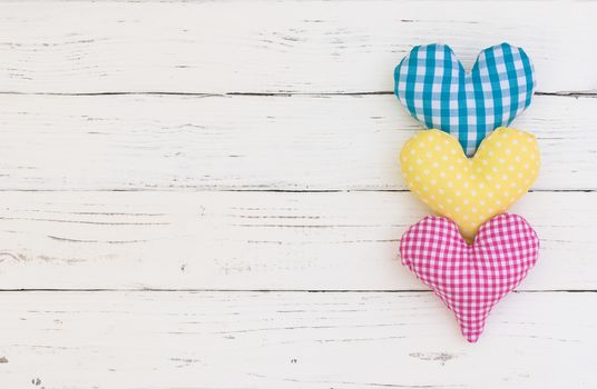 Blue, yellow and pink heart on white wood background with copy space