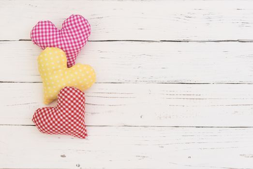 Pink, yellow and red heart border on white wooden background with copy space