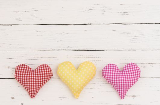 Valentine background with fabric hearts border on white wood and copy space