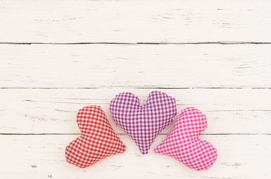 Three hearts on white wooden background with copy space