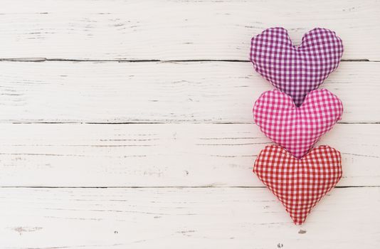 Valentine background with fabric hearts border on white wood and copy space