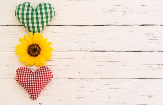 Red and green heart with yellow blossom on white wood with copy space