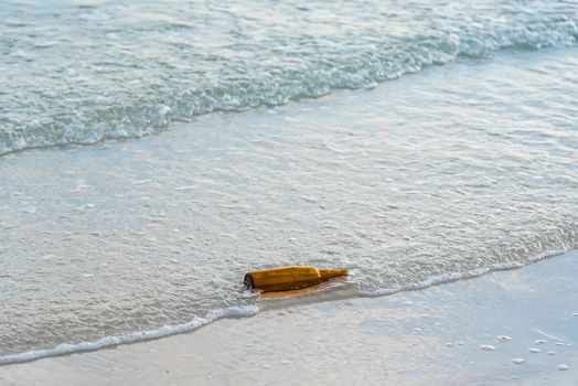 Brown glass bottle on Tawaen Beach in the dawn, the sun was rising, morning sunrise time on Koh Lan island.