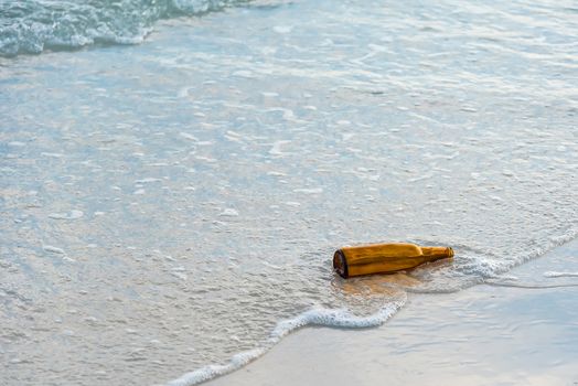 Brown glass bottle on Tawaen Beach in the dawn, the sun was rising, morning sunrise time on Koh Lan island.