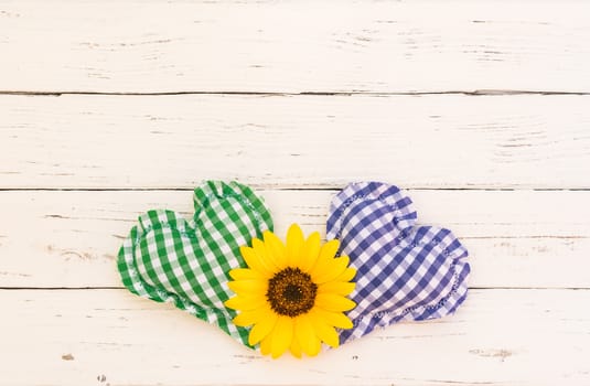 Green and blue heart background with yellow flower on white wood