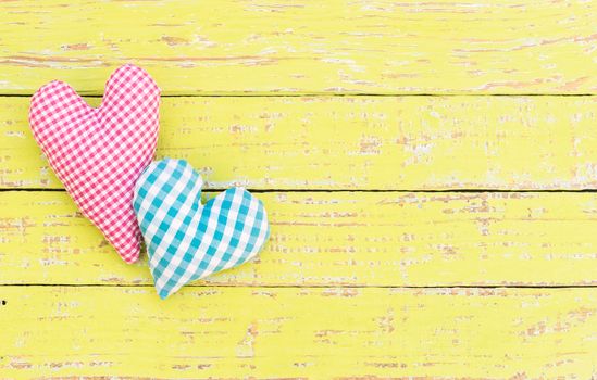 Pink and blue heart on yellow wood with copy space