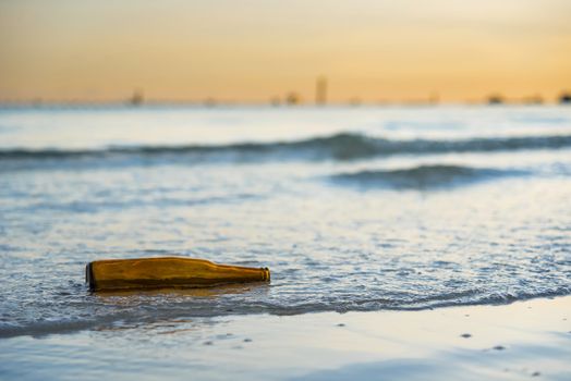 Brown glass bottle on Tawaen Beach in the dawn, the sun was rising, morning sunrise time on Koh Lan island.