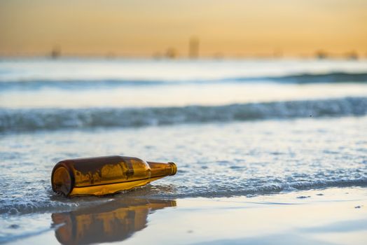 Brown glass bottle on Tawaen Beach in the dawn, the sun was rising, morning sunrise time on Koh Lan island.