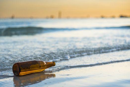 Brown glass bottle on Tawaen Beach in the dawn, the sun was rising, morning sunrise time on Koh Lan island.