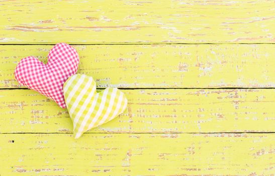 Two hearts on yellow wooden background with copy space