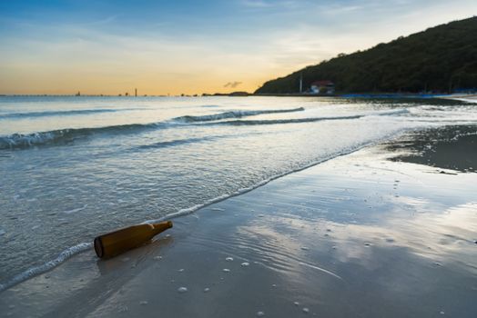 Brown glass bottle on Tawaen Beach in the dawn, the sun was rising, morning sunrise time on Koh Lan island.