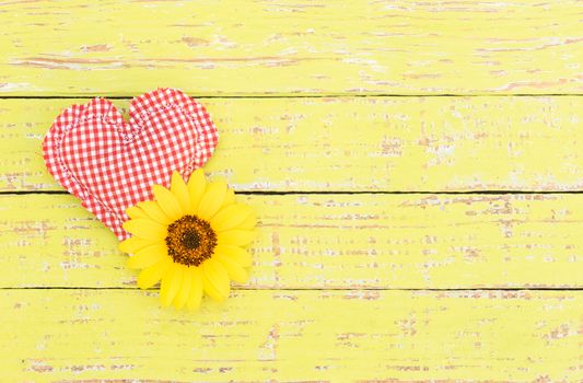 Red heart with yellow blossom on wooden background with copy space