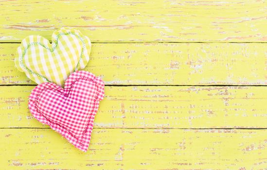 Two hearts on yellow wood background with copy space