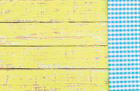Yellow wooden table background rustic texture, with blue checkered tablecloth, high angel view