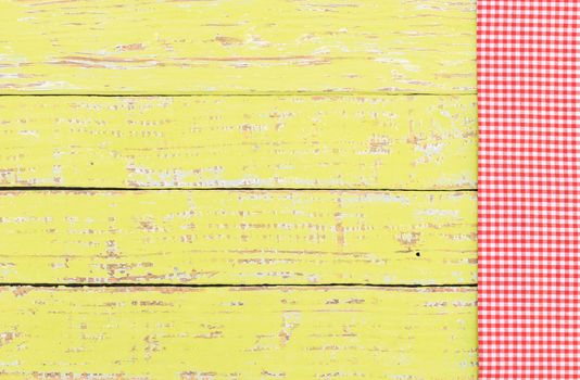 Yellow wooden table background rustic texture, with red checkered tablecloth, high angel view