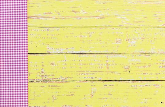 Yellow wooden table background rustic texture, with purple checkered tablecloth, high angel view