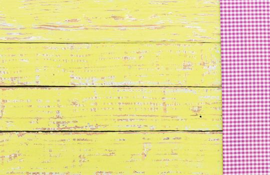 Purple checked tablecloth on rustic wooden table background, top view