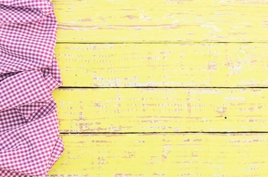 Yellow wooden table background rustic texture, with purple checkered tablecloth, high angel view

