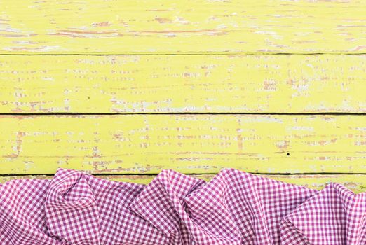Yellow wooden table background rustic texture, with purple checkered tablecloth, high angel view