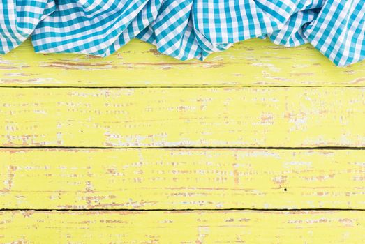Yellow wooden table background rustic texture, with blue checkered tablecloth, high angel view