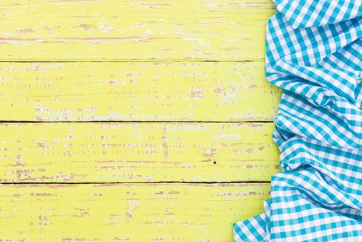 Yellow wooden table background rustic texture, with blue checkered tablecloth, high angel view