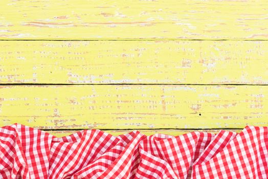 Yellow wooden table background rustic texture, with red checkered tablecloth, high angel view

