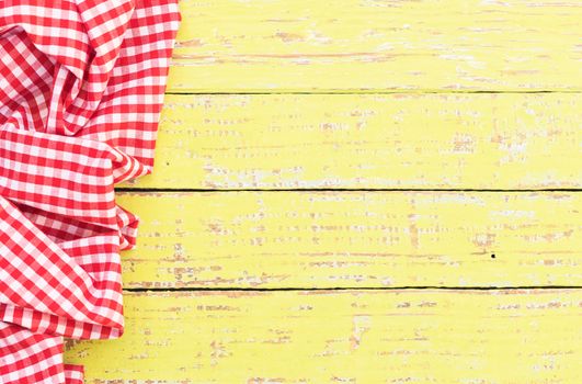 Yellow wooden table background rustic texture, with red checkered tablecloth, high angel view