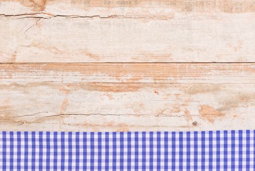 Rustic wooden table surface with blue checkered cloth, top view