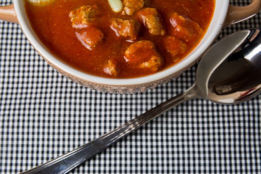 casserole with meat stew and tomato sauce on checkered tablecloth